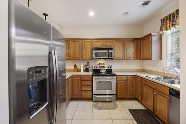 kitchen with light tile patterned floors, stainless steel appliances, hanging light fixtures, and sink