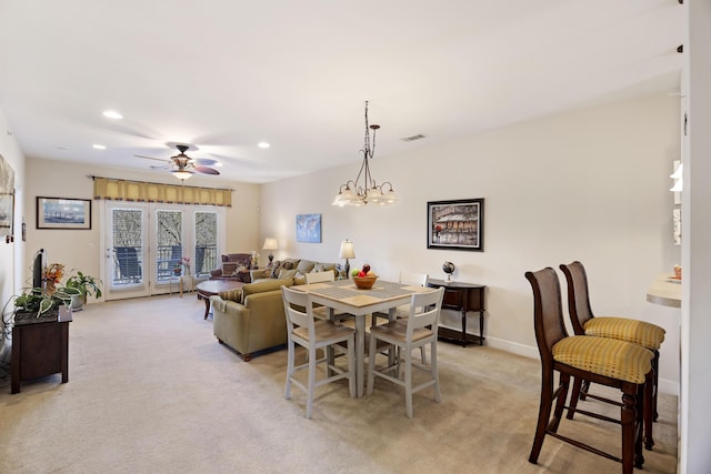 carpeted dining area featuring ceiling fan with notable chandelier