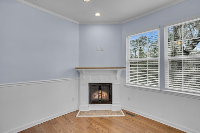 unfurnished living room featuring ornamental molding and light wood-type flooring