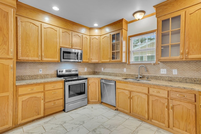 kitchen with stainless steel appliances, light stone countertops, sink, and backsplash