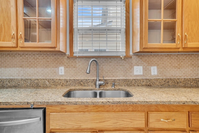 kitchen featuring light stone countertops, sink, stainless steel dishwasher, and decorative backsplash