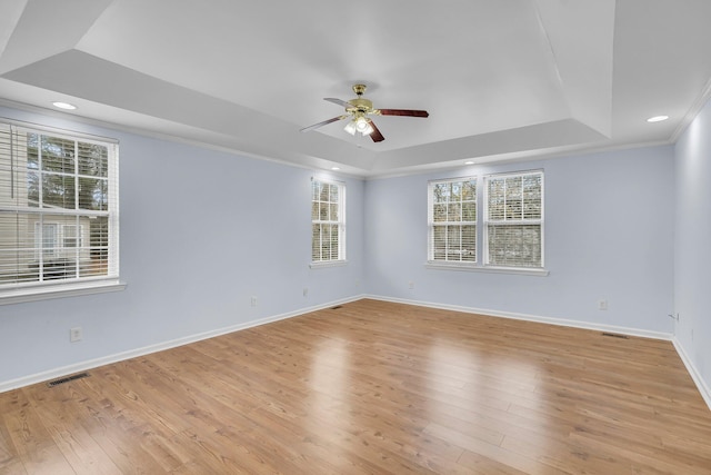 unfurnished room featuring crown molding, a raised ceiling, ceiling fan, and light wood-type flooring