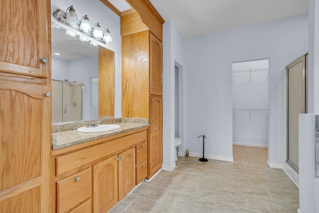 bathroom featuring vanity, a shower with shower door, and toilet