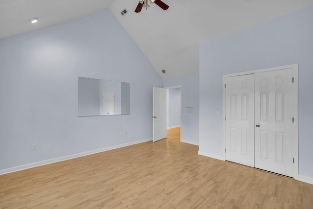 unfurnished bedroom with ceiling fan, high vaulted ceiling, a closet, and light wood-type flooring