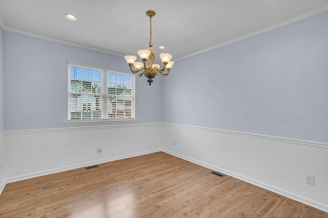 unfurnished room with ornamental molding, hardwood / wood-style floors, and an inviting chandelier