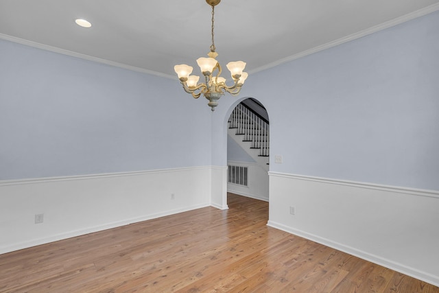 empty room with crown molding, a notable chandelier, and hardwood / wood-style flooring