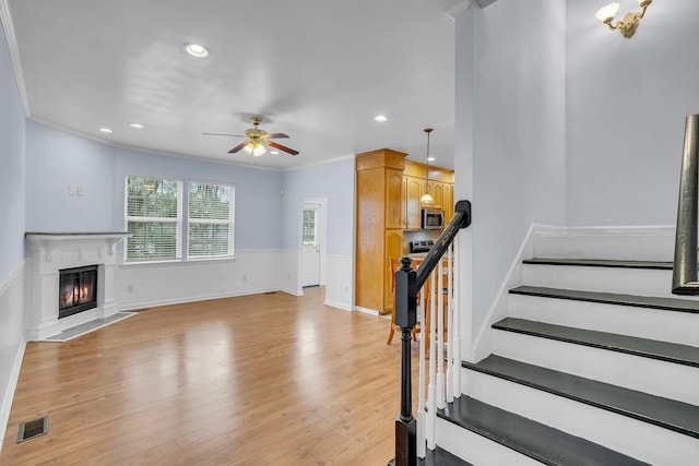 staircase featuring hardwood / wood-style floors, crown molding, and ceiling fan