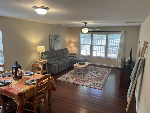 living area with a ceiling fan, visible vents, and dark wood-type flooring