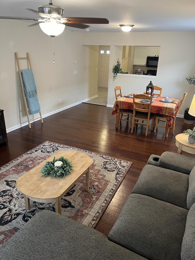 living room featuring dark wood-style floors, ceiling fan, and baseboards