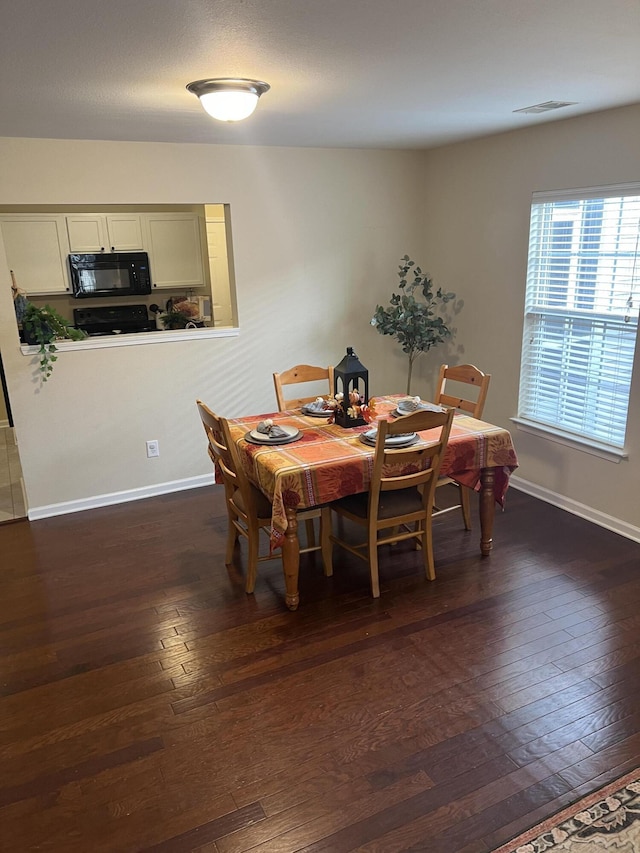 dining room featuring dark wood-style floors, visible vents, and baseboards