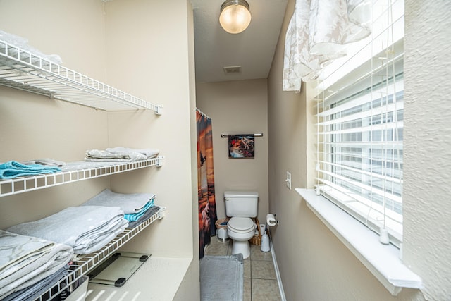 bathroom featuring toilet, baseboards, visible vents, and tile patterned floors