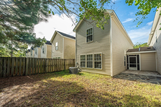 rear view of house featuring a yard, fence, central AC, and a patio