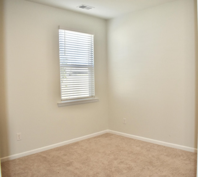 carpeted spare room with visible vents and baseboards