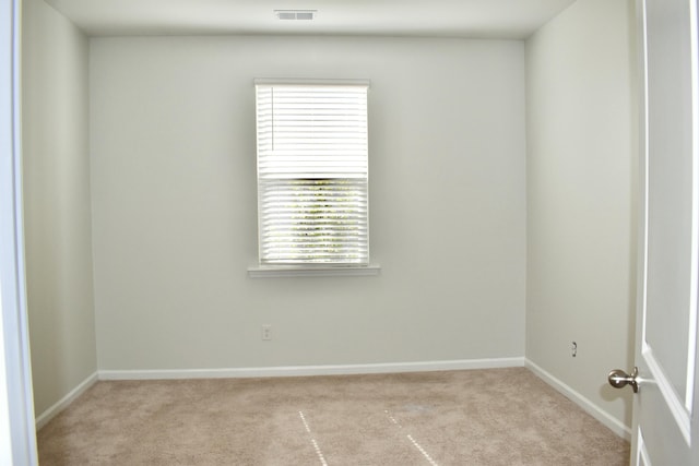 spare room featuring visible vents, light carpet, and baseboards