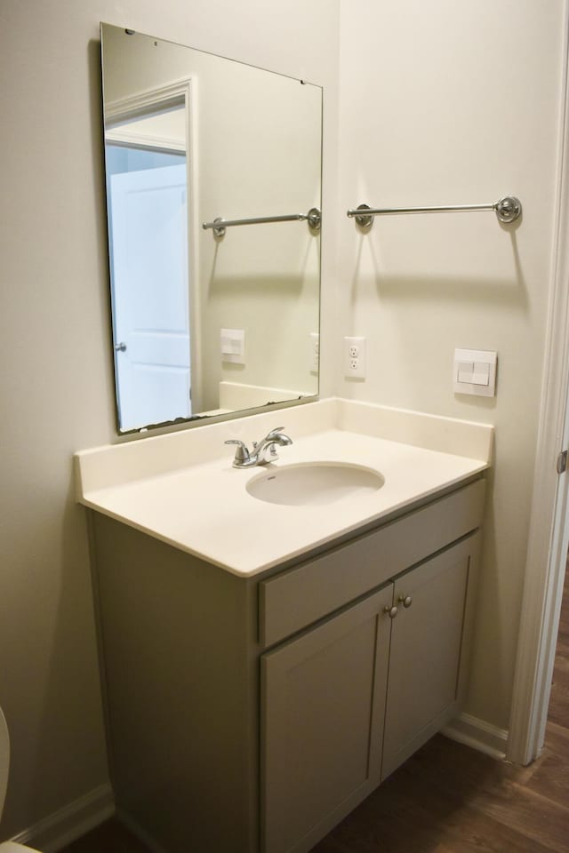 bathroom with baseboards, wood finished floors, and vanity