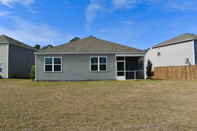 back of property with a lawn, fence, a sunroom, and a shingled roof