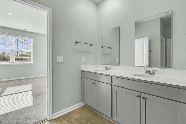 full bath with a sink, baseboards, wood finished floors, and double vanity