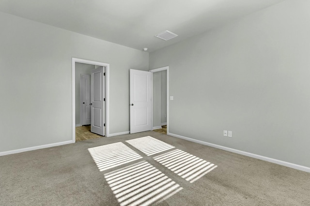 unfurnished bedroom with carpet flooring, visible vents, and baseboards