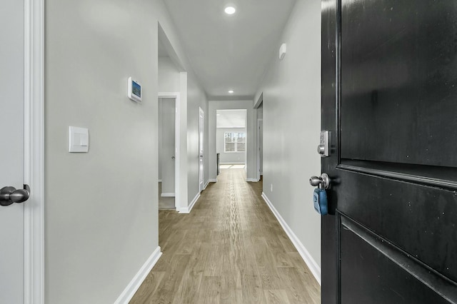 hall featuring recessed lighting, baseboards, and light wood finished floors