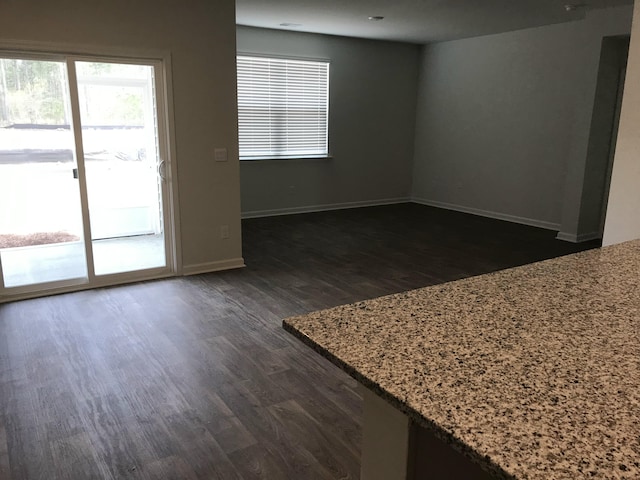 unfurnished room featuring baseboards and dark wood finished floors