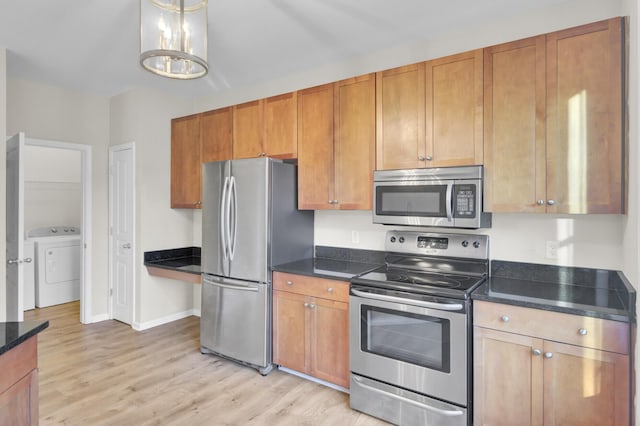 kitchen with washer / dryer, appliances with stainless steel finishes, and light hardwood / wood-style flooring