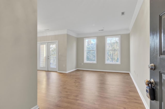 empty room featuring crown molding, french doors, and light wood-type flooring