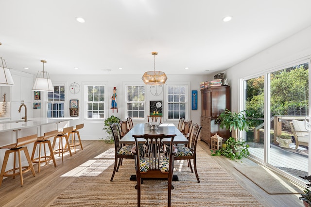 dining room with light wood-type flooring, sink, and an inviting chandelier