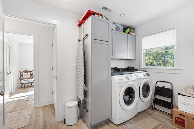 washroom with cabinets, light hardwood / wood-style flooring, and washing machine and clothes dryer