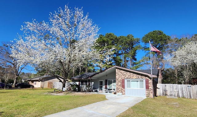 mid-century inspired home with a front yard, brick siding, and fence