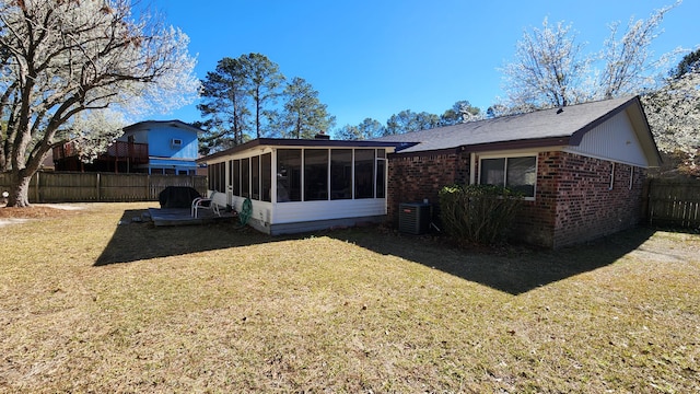 rear view of property featuring fence, a lawn, brick siding, and a sunroom