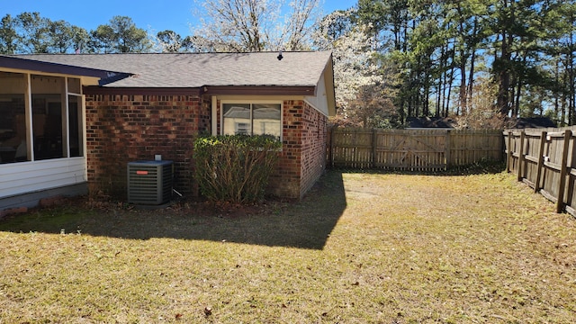 view of yard with central AC, a fenced backyard, and a sunroom