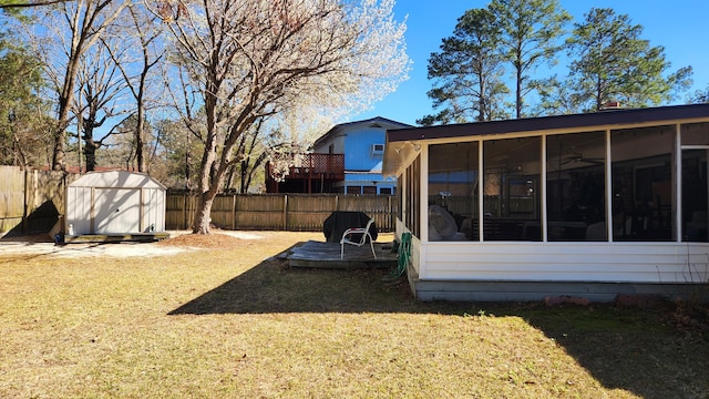 view of yard with a sunroom, a fenced backyard, an outdoor structure, and a shed