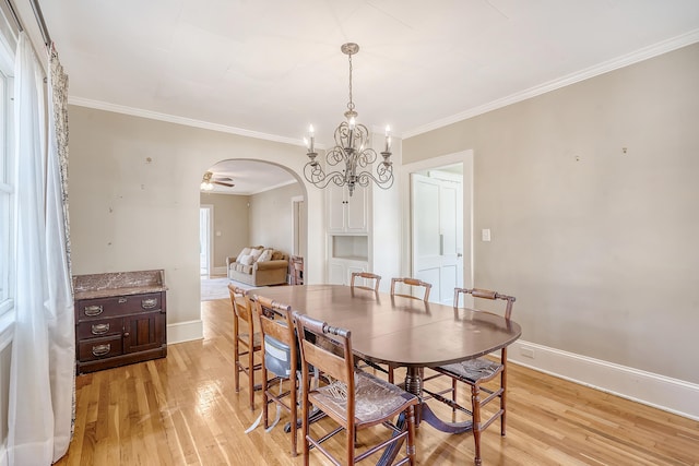 dining area featuring light hardwood / wood-style floors, ceiling fan with notable chandelier, a healthy amount of sunlight, and crown molding