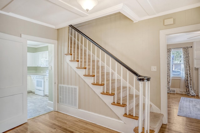 staircase with wood-type flooring and crown molding