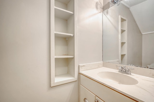 bathroom featuring built in features, vanity, and vaulted ceiling