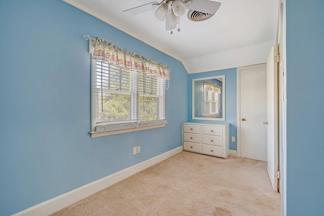 unfurnished bedroom featuring ceiling fan, vaulted ceiling, and light colored carpet