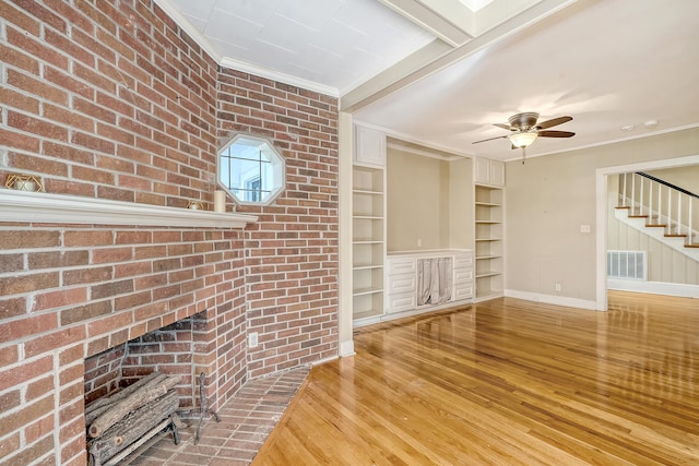 unfurnished living room featuring a fireplace, hardwood / wood-style flooring, ceiling fan, and crown molding