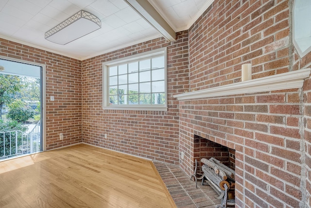 unfurnished living room with beamed ceiling, brick wall, and hardwood / wood-style flooring