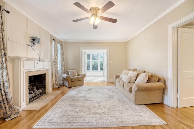 living room featuring a fireplace, ceiling fan, light wood-type flooring, and ornamental molding