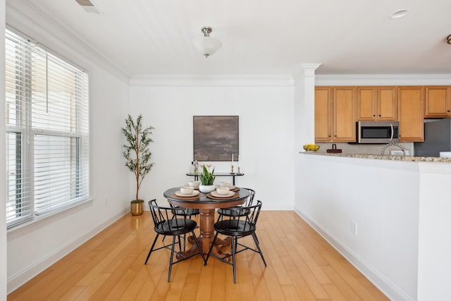 dining room with crown molding and light hardwood / wood-style floors