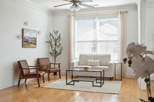 living area with crown molding, ceiling fan, and light hardwood / wood-style flooring