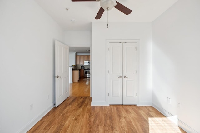 unfurnished bedroom with ceiling fan, light hardwood / wood-style flooring, and a closet