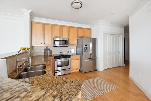 kitchen with dark stone countertops, appliances with stainless steel finishes, sink, crown molding, and decorative backsplash