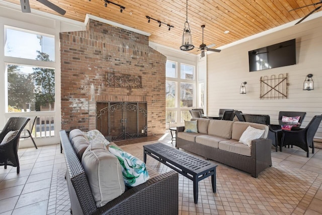 tiled living room with a brick fireplace, rail lighting, a towering ceiling, ceiling fan, and wood ceiling