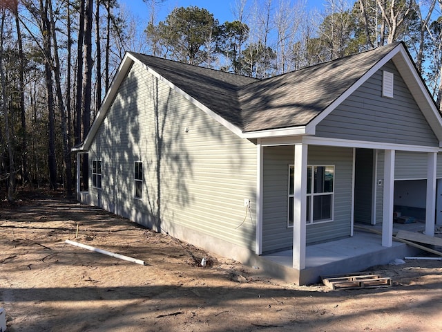 view of home's exterior featuring covered porch and roof with shingles