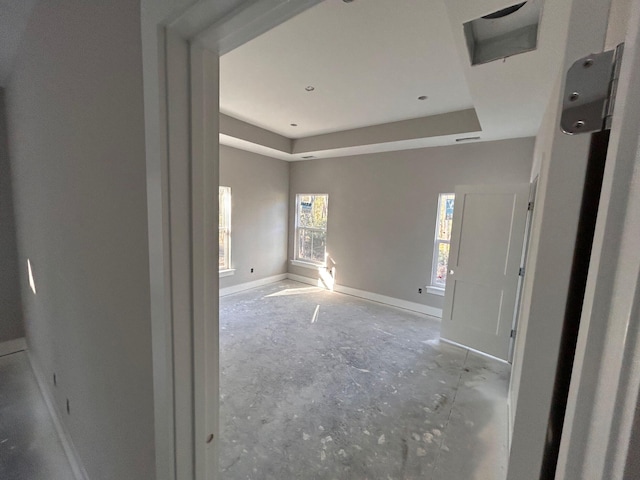 unfurnished room featuring a tray ceiling and baseboards