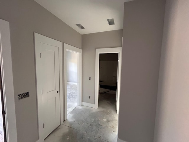 corridor with visible vents and unfinished concrete flooring