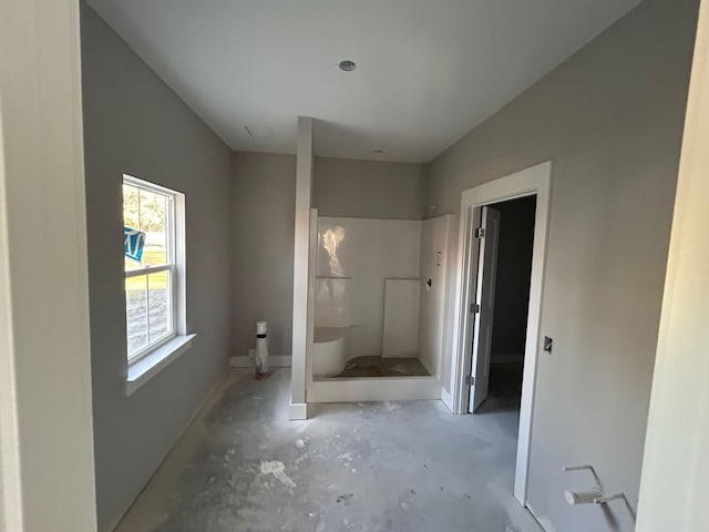 full bathroom featuring unfinished concrete flooring and a stall shower