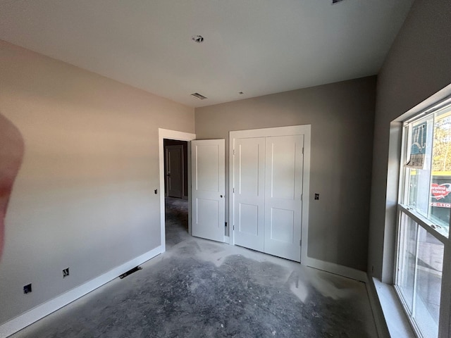 unfurnished bedroom with a closet, baseboards, visible vents, and unfinished concrete floors