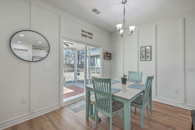 dining space featuring wood-type flooring and a notable chandelier